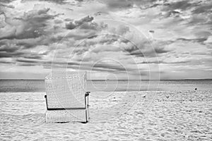 Hooded wicker basket chair on empty beach.