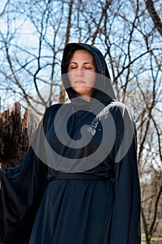 Hooded Woman in black robes deep in the Forest. Witches. Halloween and Gothic concept. Witchcraft and magic. Scary