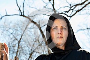 Hooded Woman in black robes deep in the Forest. Witches. Halloween and Gothic concept. Witchcraft and magic. Scary