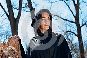 Hooded Woman in black robes deep in the Forest. Witches. Halloween and Gothic concept. Witchcraft and magic. Scary