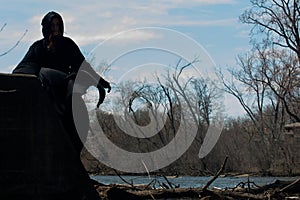 Hooded Woman in black robes in front of the Lake. Witches. Halloween and Gothic. Witchcraft and magic. Back to Nature concept