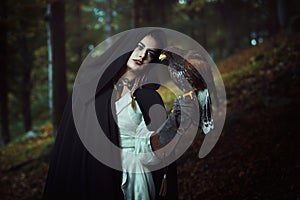 Hooded woman with hawk in dark woods