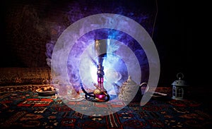 Hookah hot coals on shisha bowl making clouds of steam at Arabian interior. Oriental ornament on the carpet eastern tea ceremony.