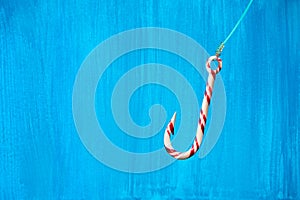 Hooked on sugar. Hook-shaped candy cane with fishing line over b
