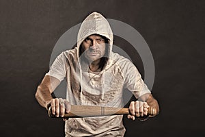 Hooligan hold baseball bat. Bearded man wear hood in hoodie tshirt. Gangster guy threaten with bat weapon. Aggression or