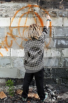 Hooligan painting graffiti on the building photo