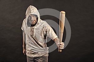 Hooligan wear hood in hoody, fashion. Man hold baseball bat, aggression. Gangster guy threaten with bat weapon