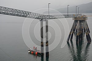 Hoonah, Alaska: Two workmen in a small boat under an unoccupied cruise ship dock photo