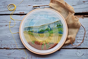 hoop with a halffinished landscape design and thread nearby