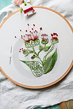 Hoop modern embroidery with botanical motifs on a wooden background