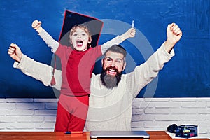 Hooray. Daddy and son raising clenched fists in hooray gesture. Father teaching her son in classroom at school. Yeah