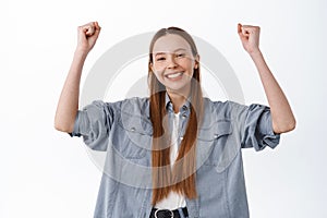 Hooray victory. Smiling happy girl winning, celebrating, raising hands up in rejoice, triumphing of success, become