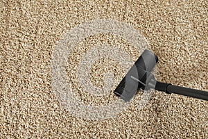 Hoovering beige carpet with modern vacuum cleaner, above view. Space for text