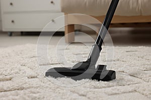 Hoovering carpet with vacuum cleaner indoors, closeup