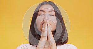 Hope concept. Portrait of praying asian woman, pleading to God, wishing something, orange studio background