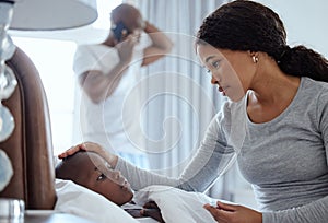 Hope hell be okay. a woman taking her little boys temperature with a thermometer in bed at home.