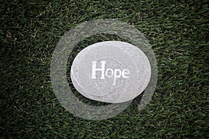 Hope. Stone with word Hope lying on green grass