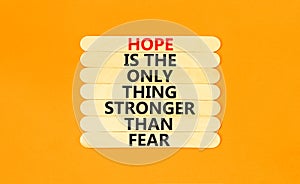 Hope stronger fear symbol. Concept words Hope is the only thing stronger than fear on wooden stick on beautiful orange table