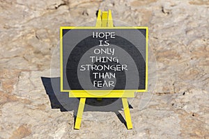 Hope stronger than fear symbol. Concept words Hope is the only thing stronger than fear on blackboard on a beautiful stone