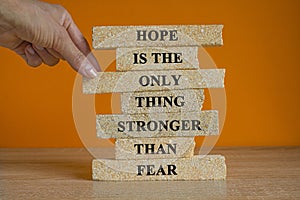 Hope stronger than fear symbol. Concept words Hope is the only thing stronger than fear on brick blocks on a beautiful orange