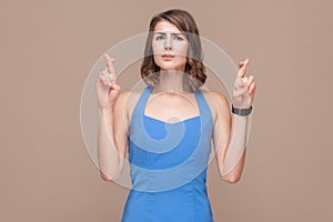 Hope, wish concept. Well dressed woman crossed fingers and looking at camera