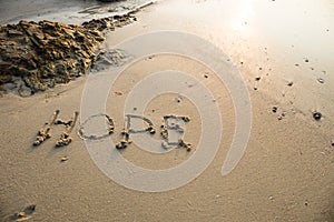 Hope written in the sand at the beach waves in the background