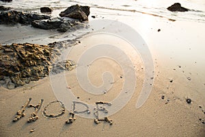 Hope written in the sand at the beach waves in the background