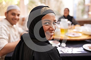 Hope you brought your appetite. Portrait of a muslim woman looking back while eating with her family.