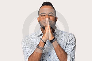 Hopeful biracial man with hands in prayer hope for luck