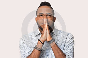 Hopeful black man  in studio join hands in prayer