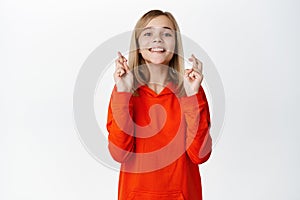 Hopeful blond girl praying, cross fingers good luck, wishing, pleading or begging to receive smth, standing over white