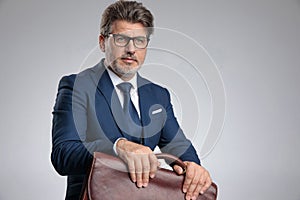 Hopeful businessman holding his suitcase and looking to the side