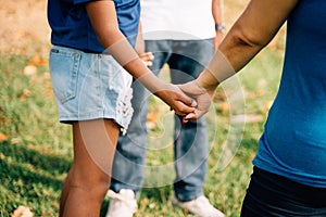 Hopeful family of father and teenage daughter, and mother holding hands together in circle and praying in outdoor park