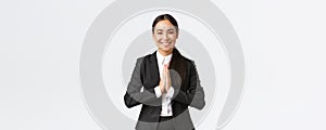 Hopeful glad asian businesswoman in black suit bowing politely and say namaste, greeting clients and smiling friendly