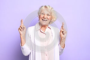 Hopeful happy kind old woman crossing fingers hoping for good luck
