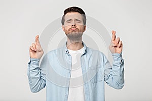 Hopeful man isolated in studio cross fingers making wish