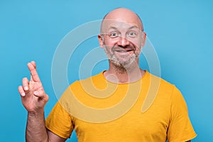 Hopeful mature male lookingat camera with fingers crossed making a wish photo