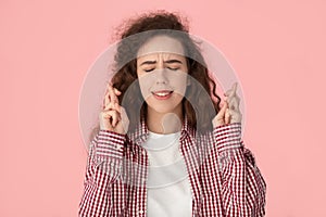 Hopeful millennial girl cross fingers making wish