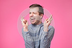 Hopeful young male crosses fingers before having job interview, worries much, wish good luck