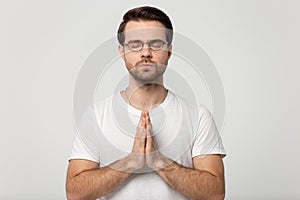 Hopeful young man in glasses praying to God.