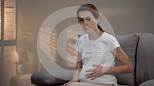 Hopeless crying pregnant marital mistreatment victim stroking belly, depression