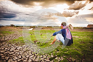 Hopeless Farmer sitting on dry ground with hoe beside him. Global warming crisis,