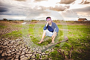 Hopeless Farmer sitting on dry ground with hoe beside him. Global warming crisis