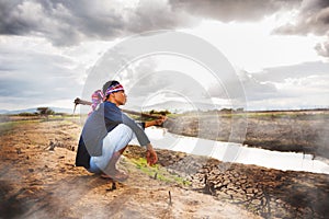 Hopeless Farmer sitting on dry ground with hoe on his shoulder and steam from ground. Global warming crisis