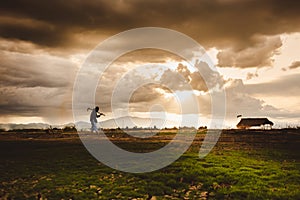 Hopeless and lonely Farmer carrying hoe and walking through his dry field at sunset. Global warming crisis