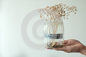 A retirement concept jar with coins and dried plant