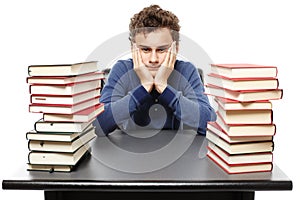 Hopeless student with face in hands sitting at his desk between