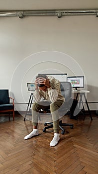 Hopeless young guy, trader holding head in despair after stock market business failure, sitting at desk, trading online