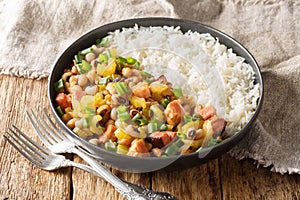 Hoppin John of black-eyed peas, bacon, sausages, vegetables and scallions with rice closeup on the plate. Horizontal