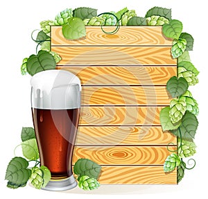 Hops branch and beer glass on a wooden background